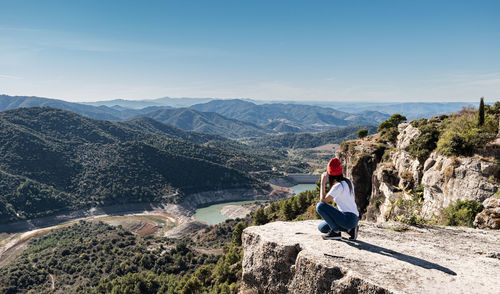 Woman on en hight mountain wearing an white t-shirt and an orange hat watching the landscape