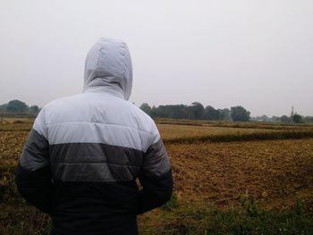 Rear view of man on field against sky