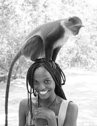 Portrait of happy woman with monkey standing outdoors