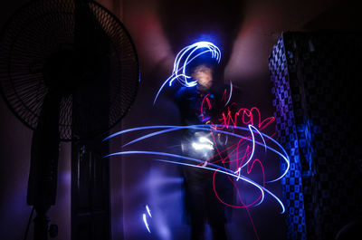 Low angle view of man standing amidst light painting