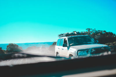 Car on road against clear blue sky