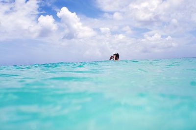 Man swimming in sea against cloudy sky