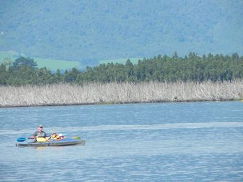 People rowing boat in river against sky