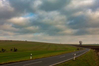 Road amidst field against sky