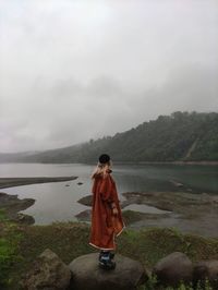 Rear view of woman standing at lakeshore