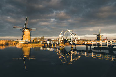 Windmill against sky by lake