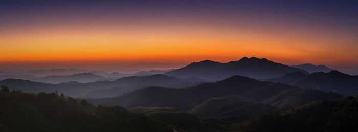 Scenic view of silhouette mountains against orange sky