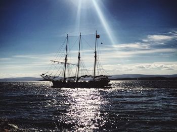 Silhouette sailboat sailing on sea against sky