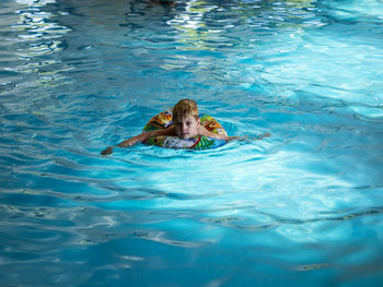 High angle portrait of boy with inflatable ring swimming in pool