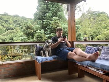 Woman with dog sitting by plants against trees