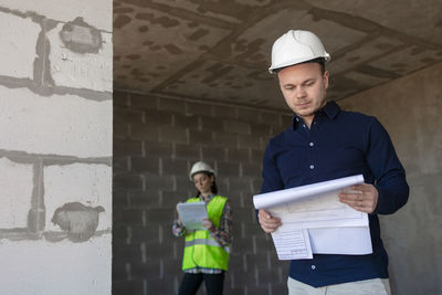 Portrait of young man standing against wall