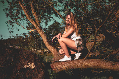 Young woman crouching on log in forest