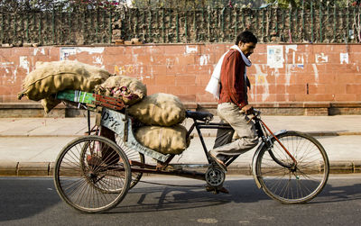 Man riding bicycle on street against wall