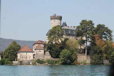 Buildings by river against clear sky