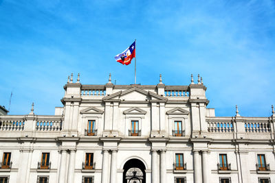 Low angle view of la moneda palace against blue sky during sunny day