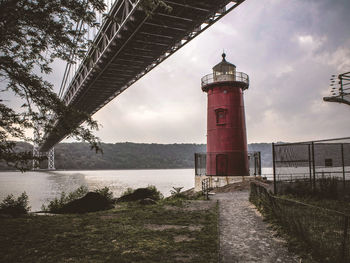 Lighthouse amidst sea and buildings against sky