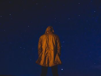 Rear view of woman standing against star field at night