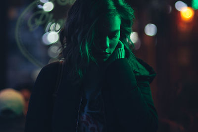 Close-up of young woman standing at night