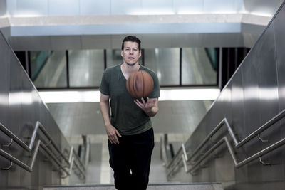 High angle portrait of young man with basketball moving up on steps