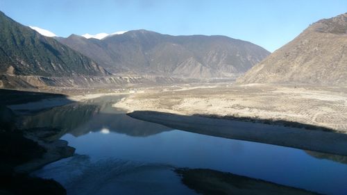 Scenic view ofriver and mountains against blue sky