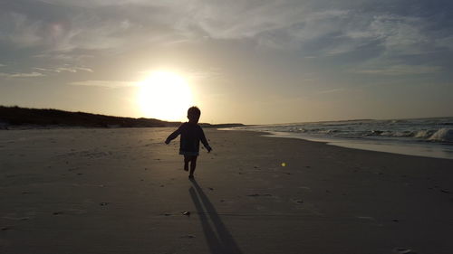 Silhouette of people on beach at sunset