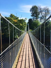 Footbridge over river against sky
