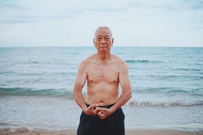 Mid adult man standing at beach against sky