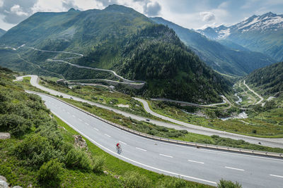 Aerial view of man riding bicycle on road amidst mountains against sky