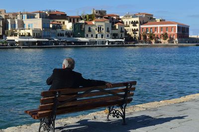 Rear view of woman sitting by sea