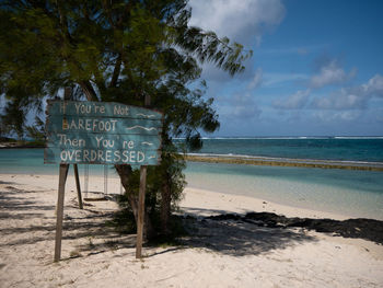 Information sign on beach against sky