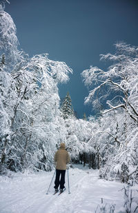 Rear view of man skiing on snow covered field