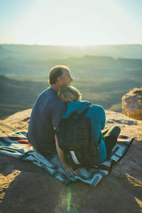 Rear view of romantic couple sitting on mountain at canyonlands national park