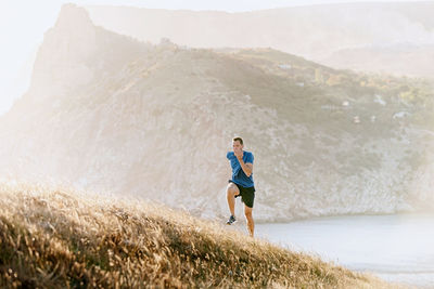 Male runner running uphill in sunset sea bay