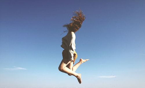 Low angle view of woman jumping in mid-air