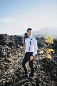 Portrait of young man standing on mountain against sky