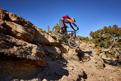 A mountain biker jumps a small cliff drop on the trail.