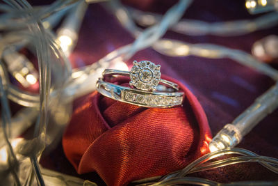 Close-up of wedding rings on ribbon amidst illuminated string lights