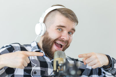 Portrait of young man holding camera over white background