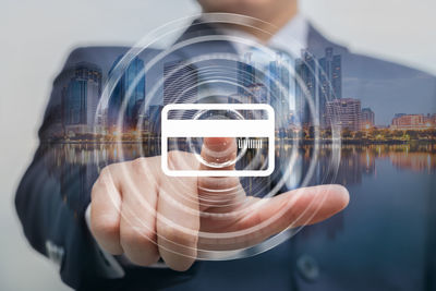 Double exposure of man touching digital screen and city by river