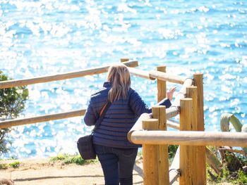 Woman standing by railing against sea