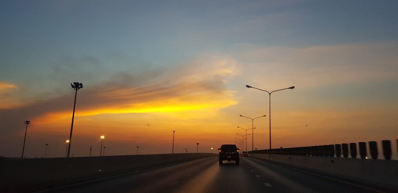 CARS ON ROAD AGAINST SKY DURING SUNSET