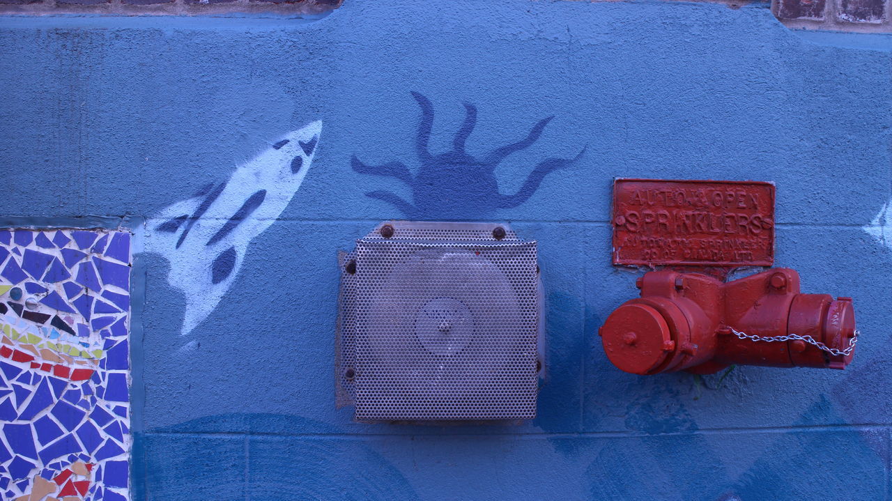 CLOSE-UP OF RED FIRE HYDRANT AGAINST WALL