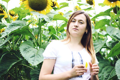 Close-up of young woman standing against plants