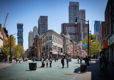 People on city street amidst buildings against sky