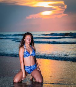 Young woman on beach against sky during sunset