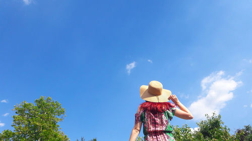 Rear view of woman standing against blue sky