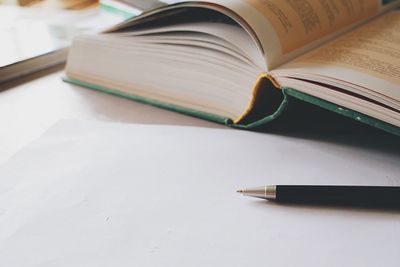 Close-up of open book pen on table