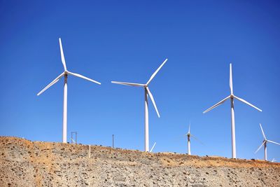 Low angle view of wind turbines on land