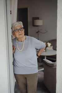 Senior woman with white hair standing at apartment doorway