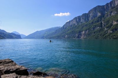 Scenic view of sea and mountains against blue sky